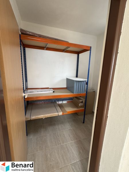 Úložný prostor v rodinném domě s policovým regálem a podlahou s dřevěným dekorem.