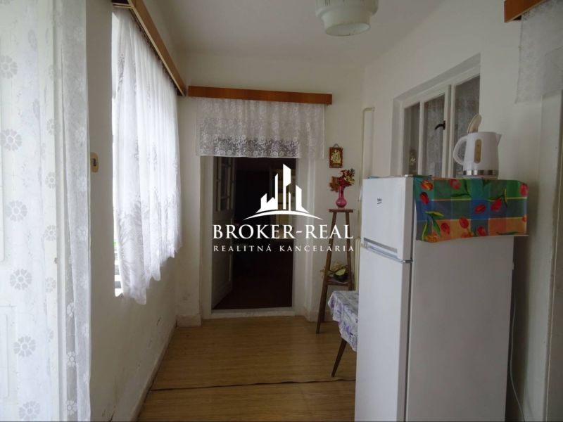 Interiér rodinného domu s bílou lednicí a dekorovanou podlahou s dřevěným dekorem.