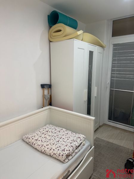 Pokoj s postelí, šatní skříní a srolovanými matracemi v 2-pokojovém bytě.