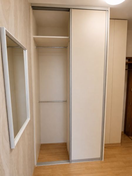 Vestavěná šatní skříň s posuvnými dveřmi a podlahou s dřevěným dekorem v 2pokojovém bytě.
