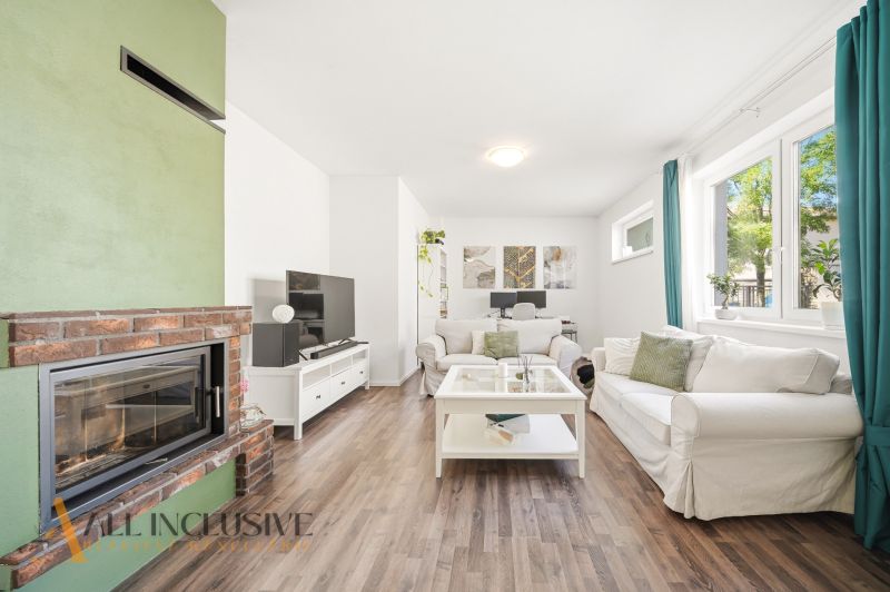 Obývací pokoj s krbem, TV stolkem a podlahou s dřevěným dekorem ve 3pokojovém bytě.