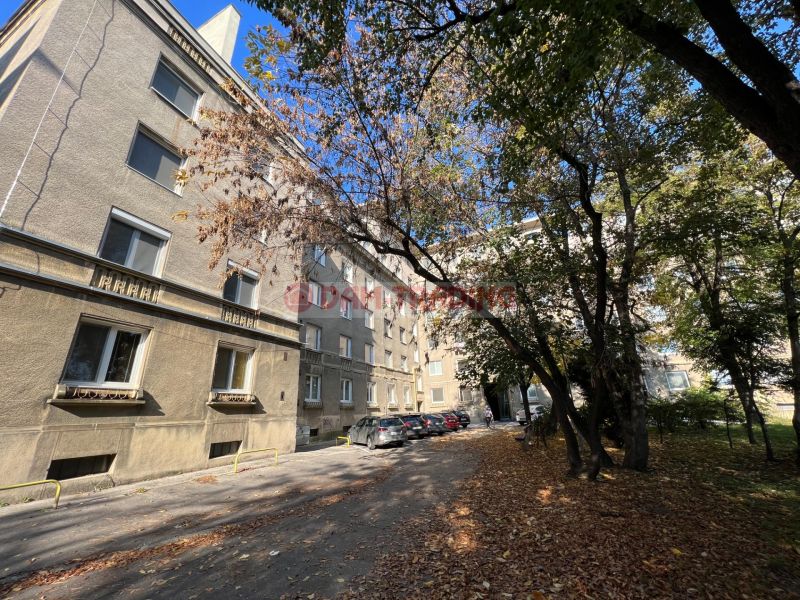 Bytový dům na Miletičově ulici v Bratislavě - Ružinově, obklopený stromy a auty.