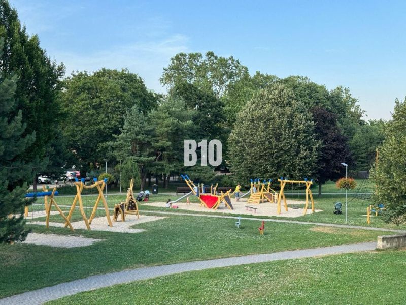 Dětské hřiště na Měsíční ulici v Bratislavě II plné barevného vybavení a zeleně.