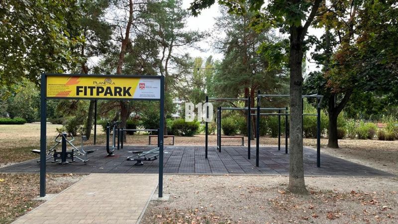 Fitpark s venkovním posilovacím zařízením, obklopený zelení v parku.