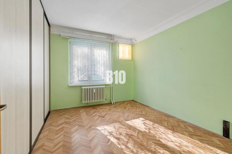 Pokoj s podlahou s dřevěným dekorem a zelenými stěnami v 2pokojovém bytě.