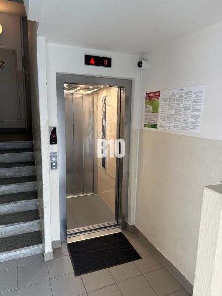 Otevřený výtah vedle schodiště v bytovém domě, 2-pokojový byt.