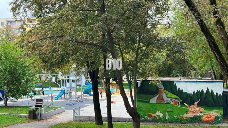 Park s dětským hřištěm mezi stromy v Bratislavě II, na ulici Měsíční.