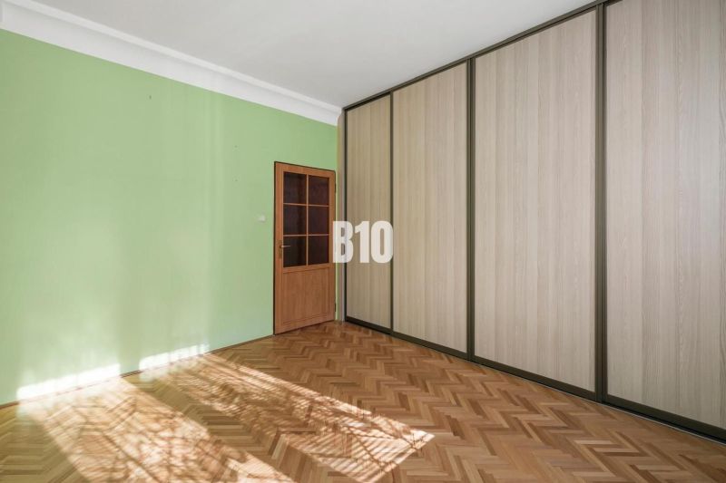 Pokoj v 2pokojovém bytě s velkými skříněmi a podlahou s dřevěným dekorem.