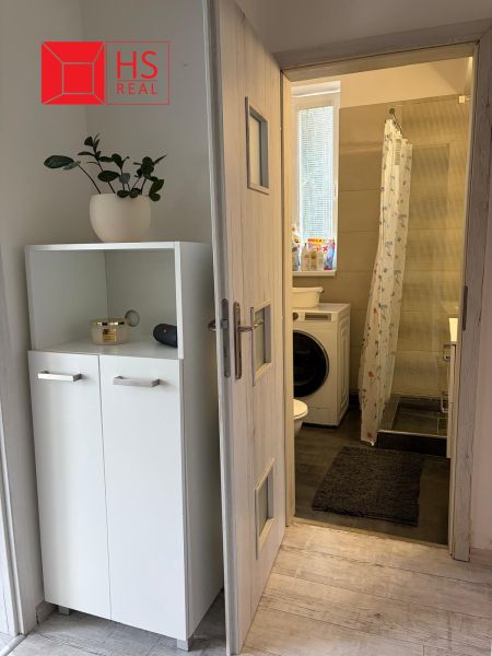 Interiér 2-pokojového bytu s koupelnou, skříňkou a pračkou.