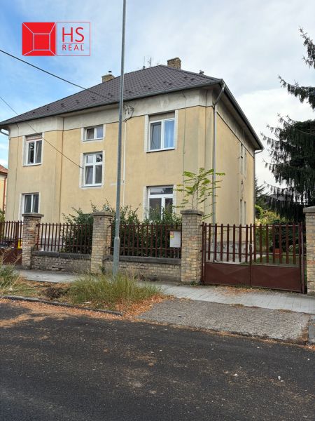 Dvoupatrový bytový dům na Komenského ulici v Nových Zámcích s oplocením z cihel.