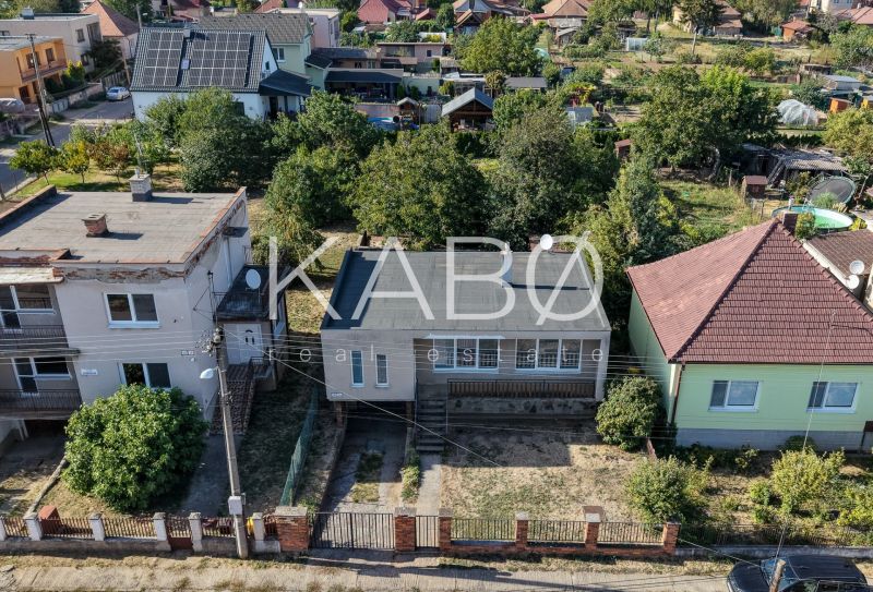 Letecký pohled na řadu rodinných domů v Ivance pri Nitre se zahradami a stromy.