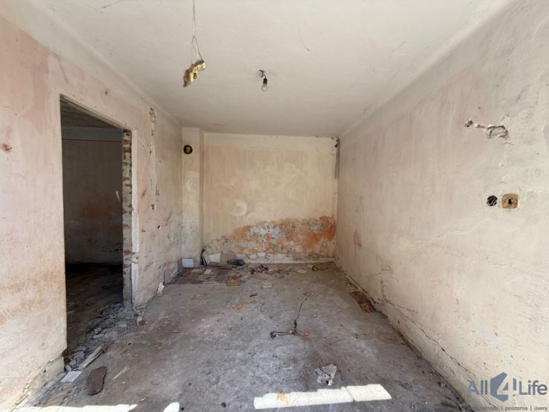 Pokoj v rodinném domě před rekonstrukcí s odkrytými stěnami a podlahou.