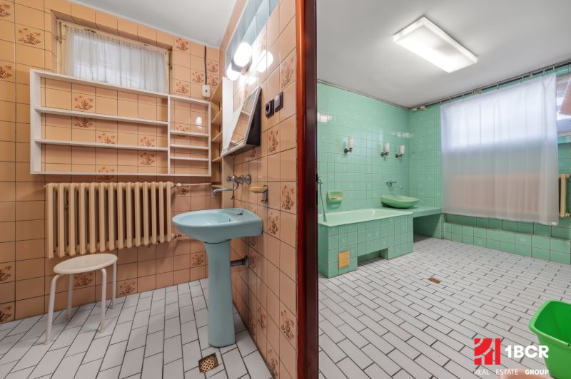 Koupelna v rodinném domě se zelenými dlaždicemi a modrým umyvadlem, retro design.