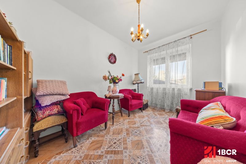 Obývací pokoj v rodinném domě s červenými křesly a stolkem na podlaze s dřevěným dekorem.