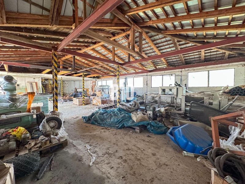 Prostorný interiér rodinného domu s kovovou střechou a různým uskladněným materiálem.