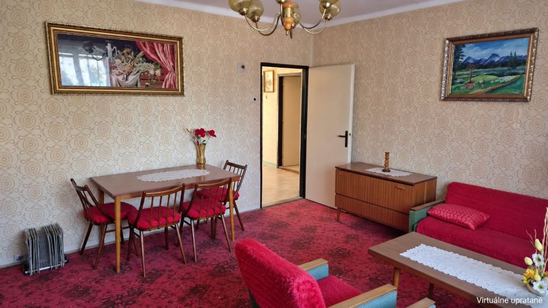 Obývací pokoj s květinovou dekorací v rodinném domě, červená křesla, vzorovaný koberec.