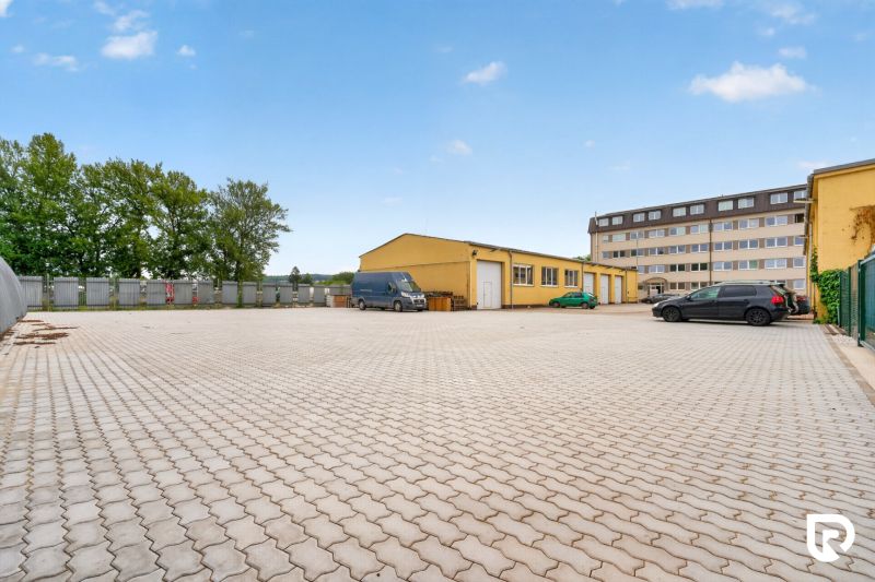 Parkoviště a žlutá budova na Brněnské ulici v Trenčíně, vhodné pro kanceláře.