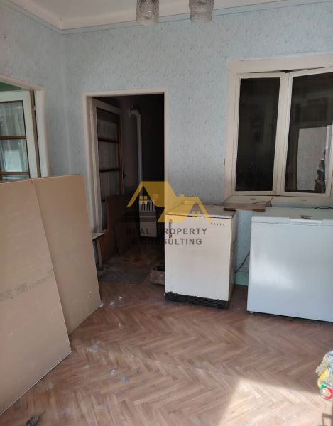 Pokoj v rodinném domě s podlahou s dřevěným dekorem a starším nábytkem.