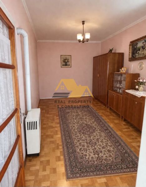 Interiér rodinného domu s podlahou s dřevěným dekorem, kobercem a skříňkami.