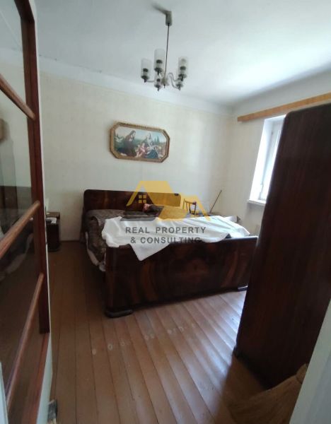Ložnice v rodinném domě s podlahou s dřevěným dekorem a obrazem na stěně.
