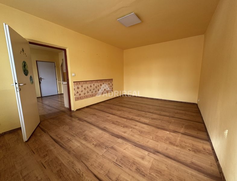 Pokoj s podlahou s dřevěným dekorem v 1-pokojovém bytě se žlutými stěnami.