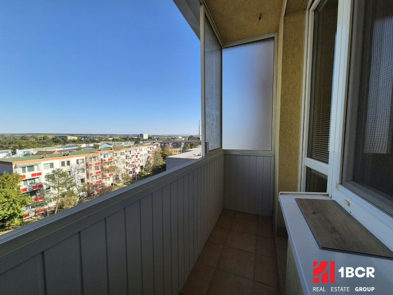 Balkon garsonky s výhledem na Bystrickou ulici v Pezinku, slunečný den.