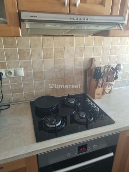 Kuchyňská linka s varnou deskou a digestoří ve 3-pokojovém bytě, obložená kachličkami.