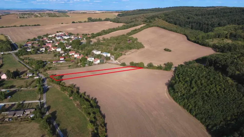 Letecký pohled na zemědělské a lesní pozemky u Podhájské obklopené obcí a lesem.