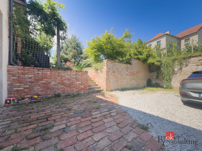 Exteriér 3-pokojového bytu na Čajakově ulici v Bratislavě-Novém Městě s cihlovým plotem.