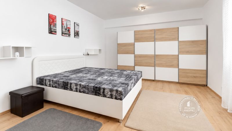 Ložnice s postelí, šatní skříní a podlahou s dřevěným dekorem v 2pokojovém bytě.
