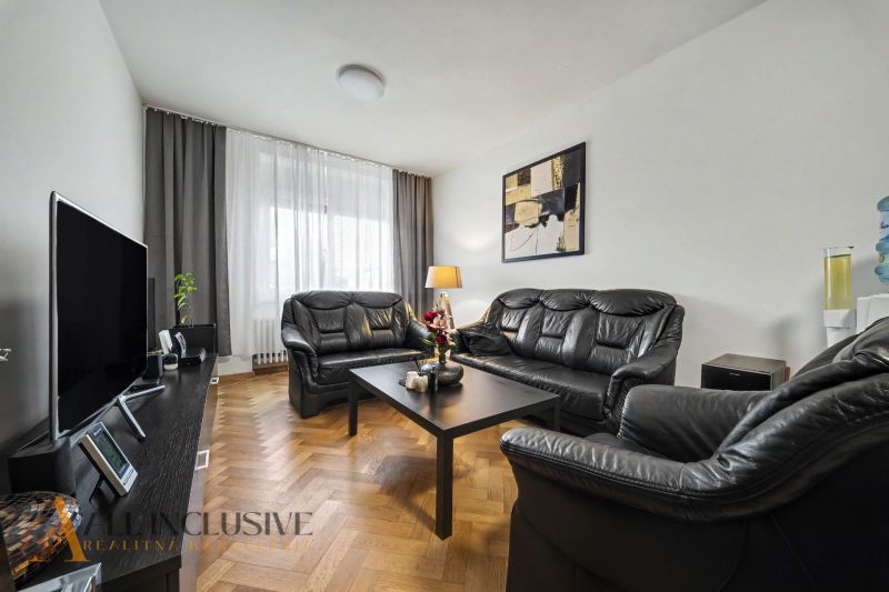 Obývací pokoj v rodinném domě s černým koženým nábytkem a televizí.