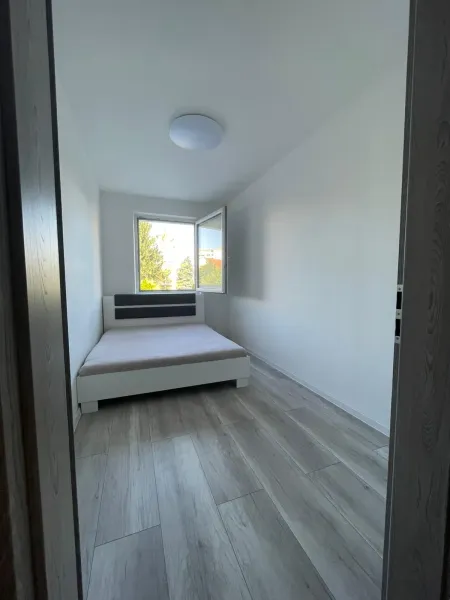 Ložnice s postelí a podlahou s dřevěným dekorem v 2pokojovém bytě.