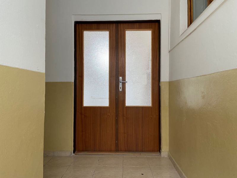 V kancelářích jsou dvoukřídlé dveře se zasklením a světle hnědými stěnami.