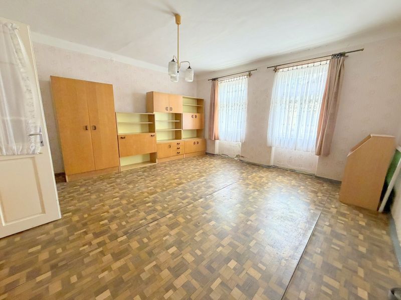Prostorný obývací pokoj v rodinném domě s vestavěnými skříněmi a podlahou s dřevěným dekorem.