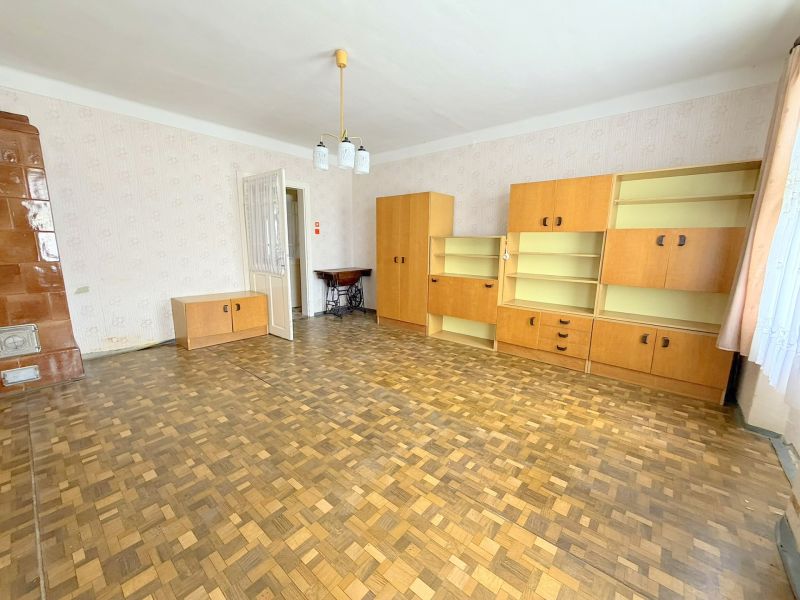 Obývací pokoj s podlahou s dřevěným dekorem, světlým nábytkem a krbovými kamny v rodinném domě.