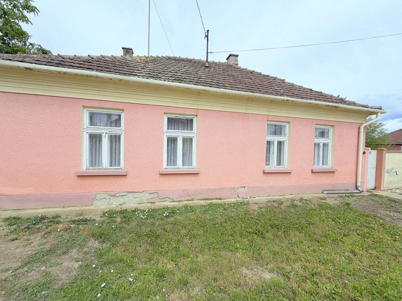 Rodinný dům v Dunakiliti s růžovou fasádou a čtyřmi okny v přízemí.
