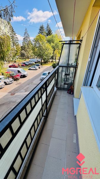 Balkon s výhledem na stromy a auta na Nádražní v Partizánském, prostor 3pokojového bytu.