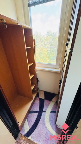 Šatna v 3-pokojovém bytě s výhledem přes velké okno a barevným kobercem.