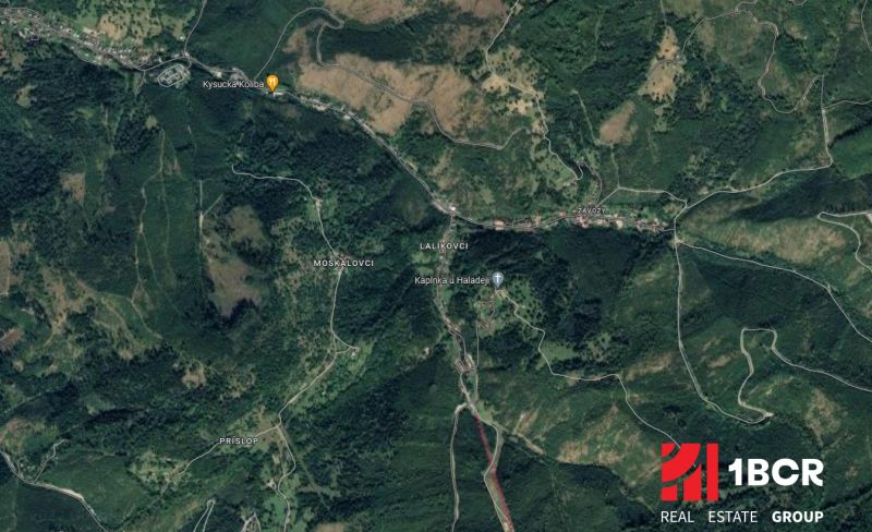 Letecký pohled na Oščadnicu s okolními zalesněnými oblastmi, cestami a stavbami.