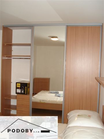 Ložnice s podlahou s dřevěným dekorem a vestavěnou skříní v 3pokojovém bytě.