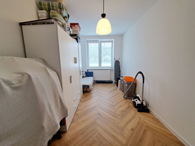 Světlý pokoj ve 3-pokojovém bytě s podlahou s dřevěným dekorem a úložným prostorem.