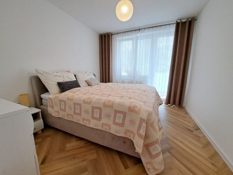 Ložnice s manželskou postelí a podlahou s dřevěným dekorem ve 3pokojovém bytě.