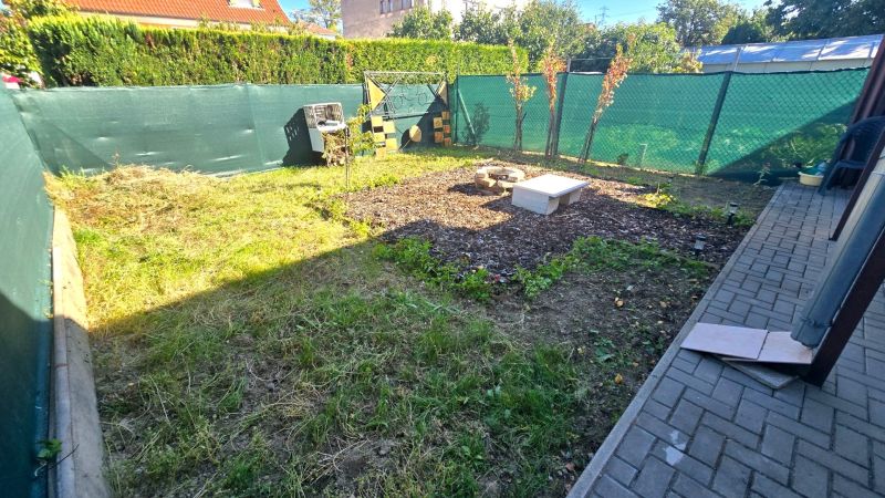 Zahrada rodinného domu na Kupeckého ulici v Piešťanech s trávníkem a záhonem.