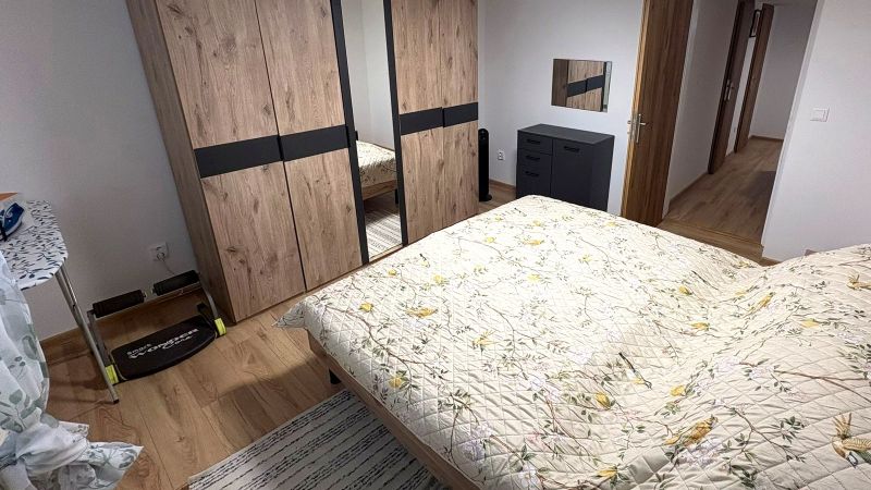 Ložnice s postelí, skříní a podlahou s dřevěným dekorem v rodinném domě.