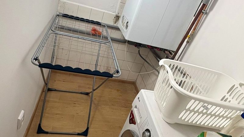 Prádelna v rodinném domě s pračkou, sušákem a podlahou s dřevěným dekorem.