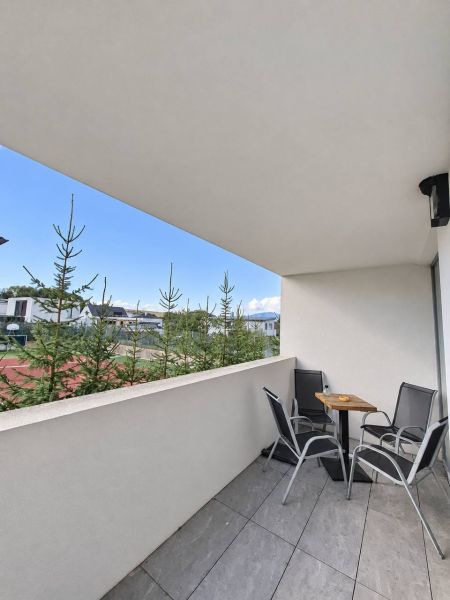 Balkon 2pokojového bytu s posezením, výhledem na zeleň a moderní dlažbou.