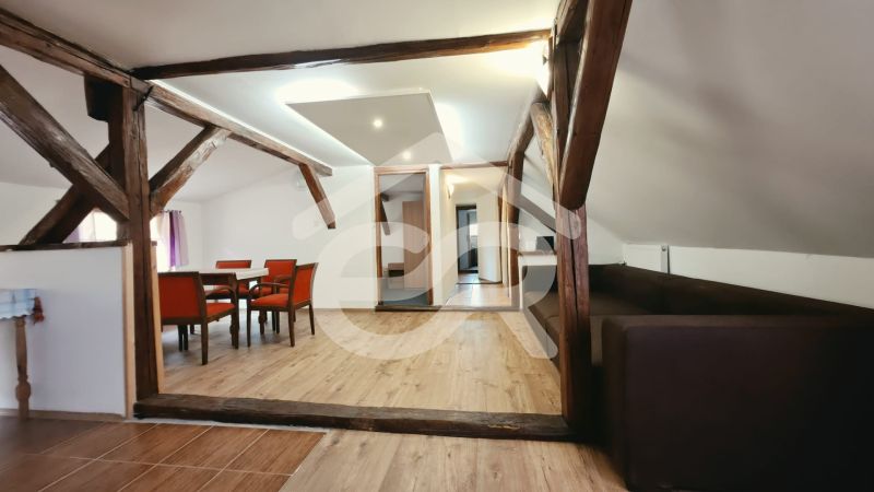 Rekreační apartmán s podlahou s dřevěným dekorem, dřevěnými trámy a pohodlným nábytkem.