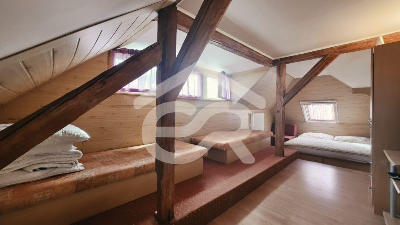 Podkrovní pokoj v rekreačním apartmánu s podlahou s dřevěným dekorem a lůžky.