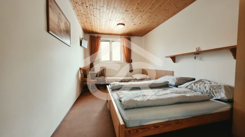 Ložnice v rekreačním apartmánu se dvěma postelemi a TV, podlaha s dřevěným dekorem.