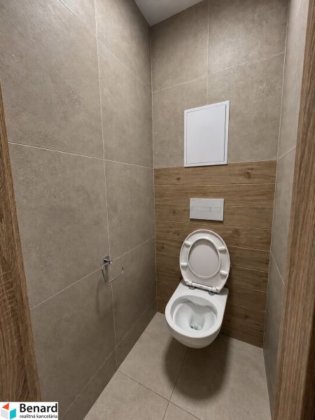 WC s keramickými obklady a podlahou s dřevěným dekorem ve 2pokojovém bytě.